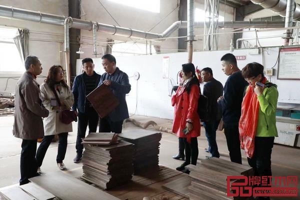恒达木业董事长陈国良（左四）带领嘉宾参观工厂