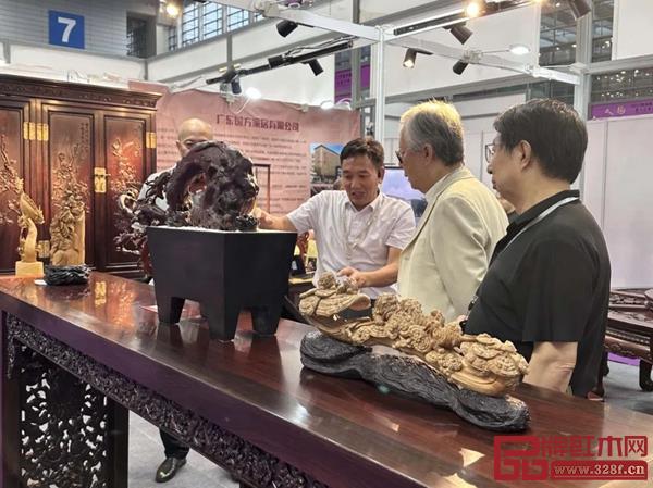 高级工艺美术师、国方家居创始人陈新平（右三）为观展者讲解木雕工艺