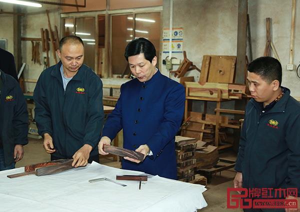  中国传统工艺大师，东成红木董事长张锡复（右二）经常与团队就红木家具制造分析查找原因，提出具体的改进意见