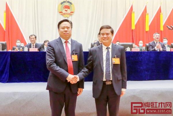 监利市政协上届主席汤吉银（右）和新当选的市政协主席廖和平（左）在主席台前握手交接