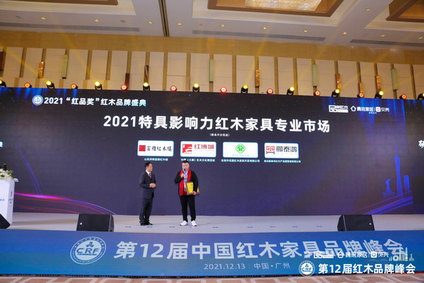 富雅红木楼董事长杨少辉（右）上台接受“2021特具影响力红木家具专业市场”颁牌